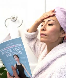 Fumiko Takatsu in the bathroom reading the Ultimate Guide to the Face Yoga Method