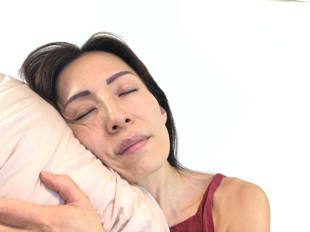 Fumiko Takatsu with her head on a pillow showing a sleep position that's causing asymmetrical face.  
