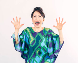 Fumiko Takatsu with arms raised in the air making a happy face.