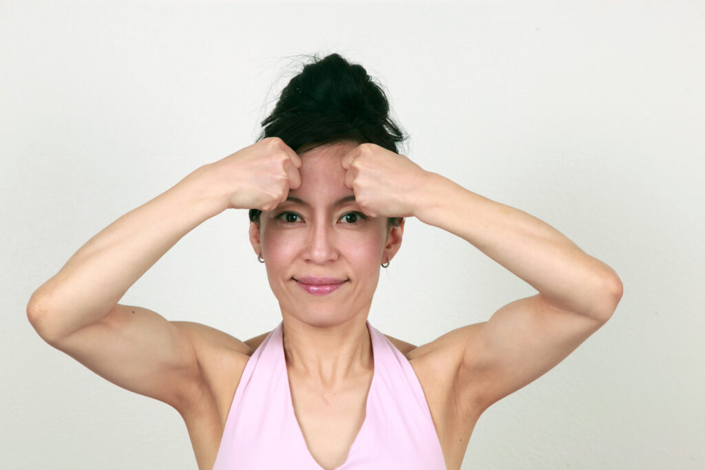 Fumiko Takatsu pressing her forehead with the knuckles while doing a pose for frown lines. 