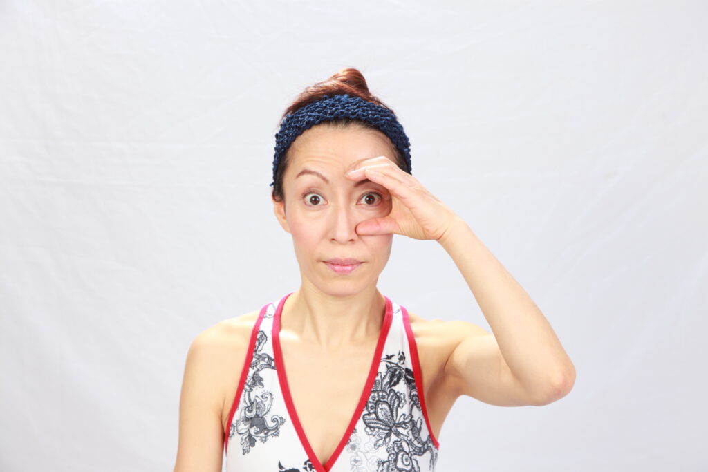 A woman doing a face yoga exercise for droopy eyelids. 