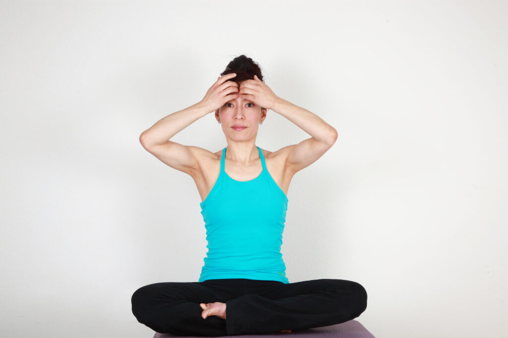 A woman doing a face yoga exercises for tired eyes. 