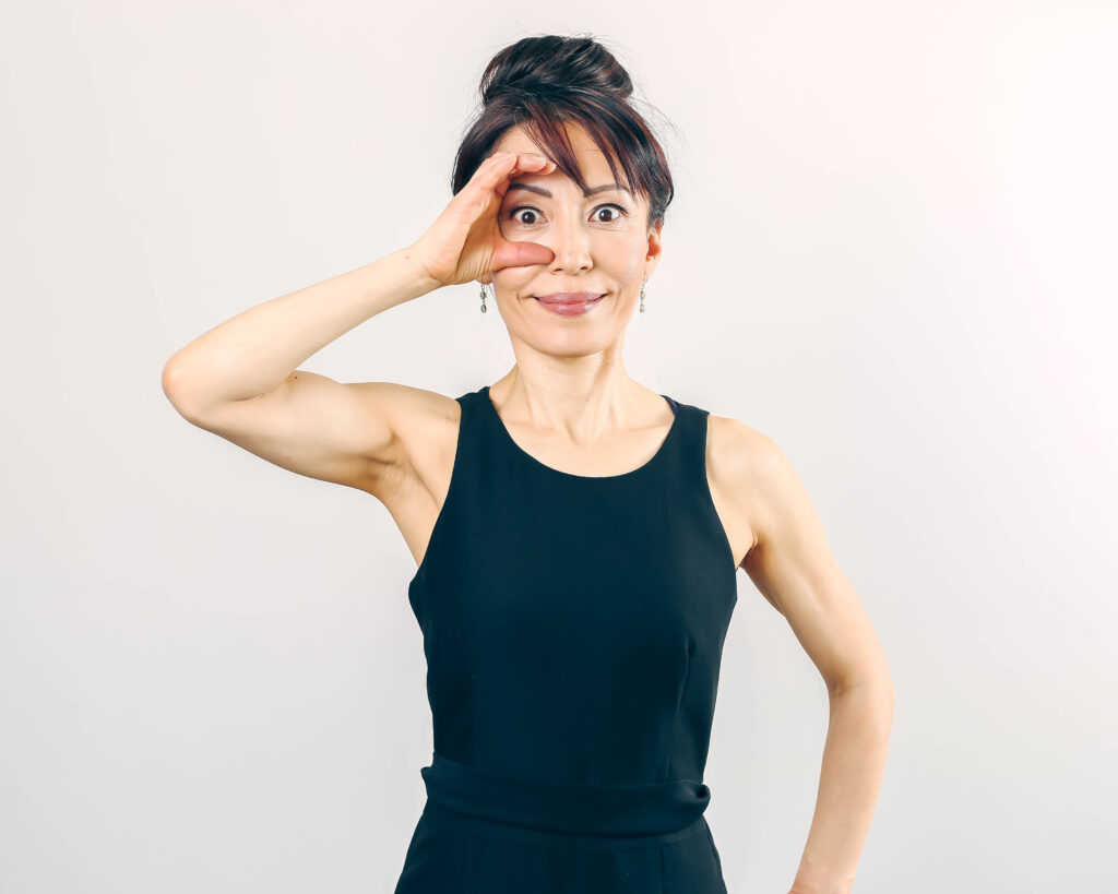 A woman in a black top practicing Face Yoga for the eye area. 