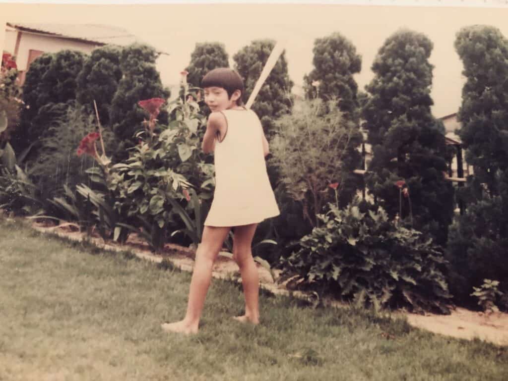 A girl in a white dress holding a bat. 
