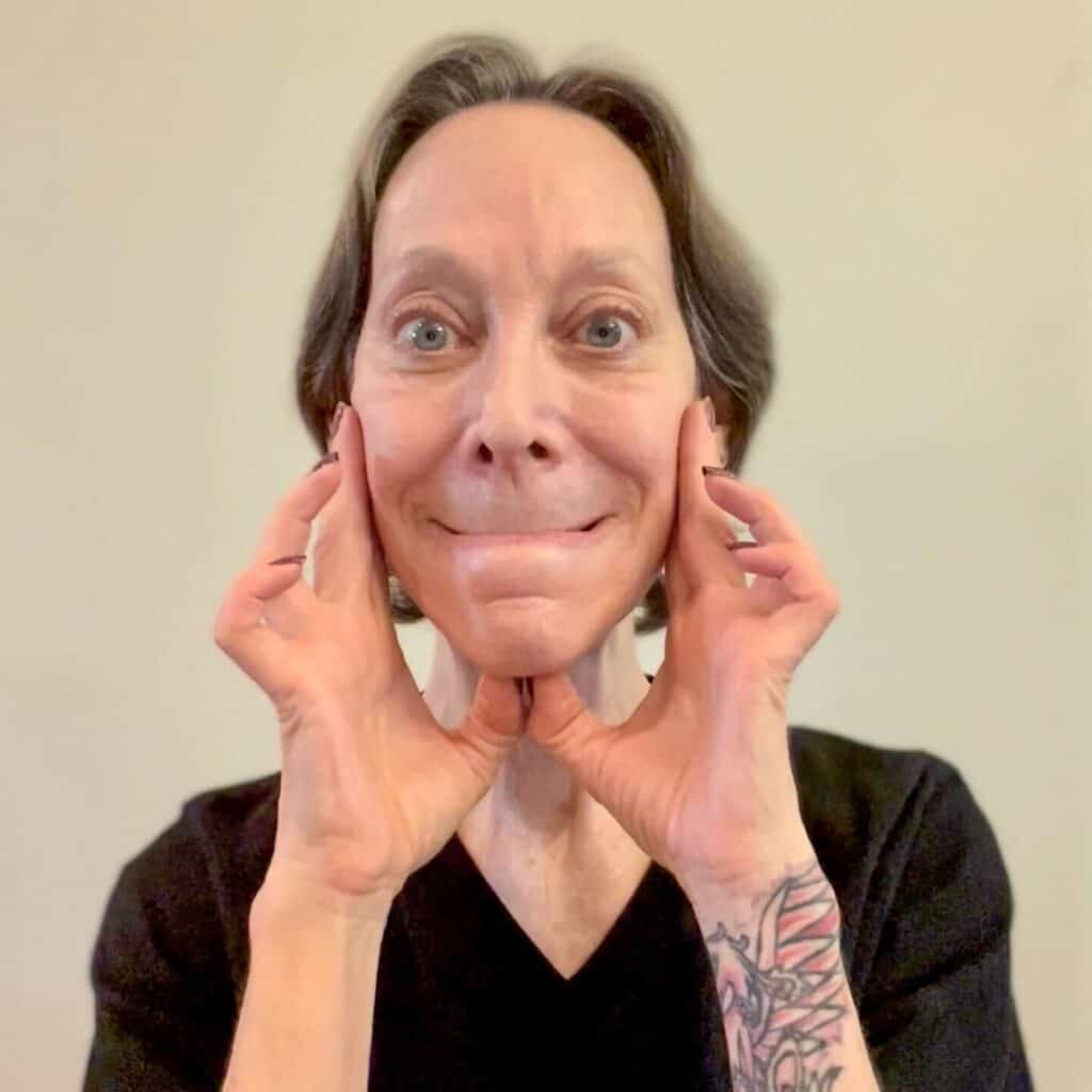 A woman doing a face yoga pose.
