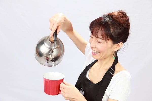 Fumiko smiling and pouring hot water into mug