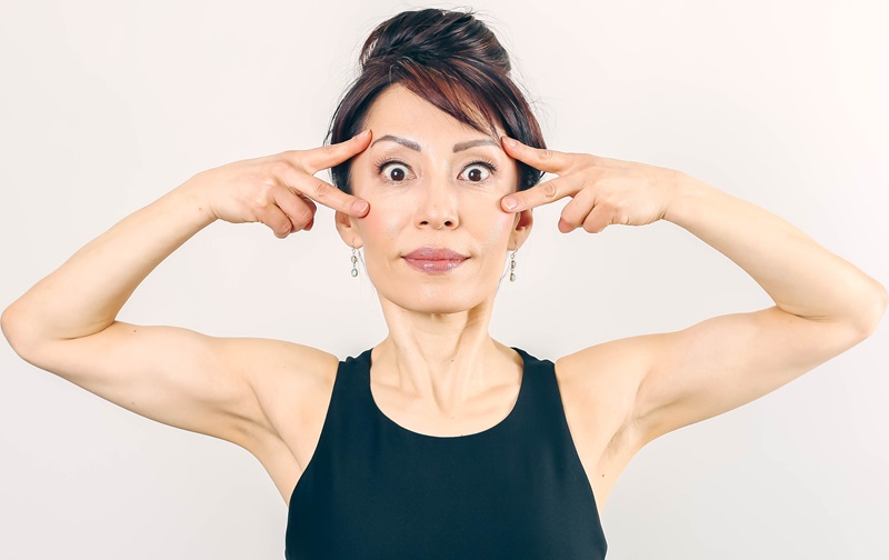 Woman doing the face yoga pose for the eye bags