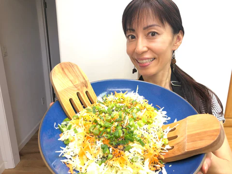 A woman holding big blue plate of fresh salad